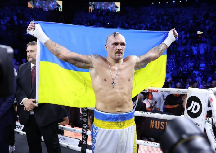 Oleksandr Usyk holds the flag of Ukraine during his boxing bout