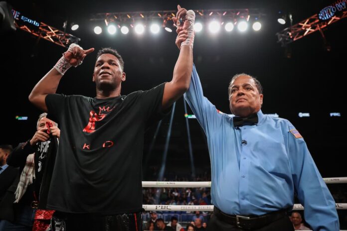 Referee Rafael Ramos raises Lenier Pero's hand in victory after his boxing match against Viktor Faust
