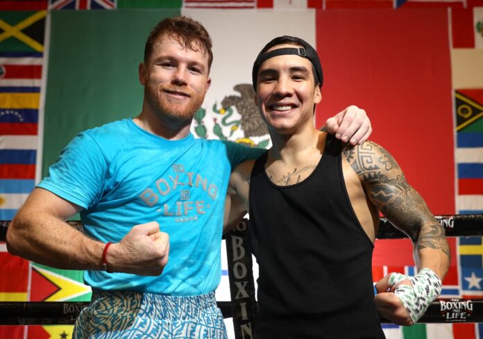 Canelo Alvarez and Oscar Valdez posing together in a boxing ring during training camp