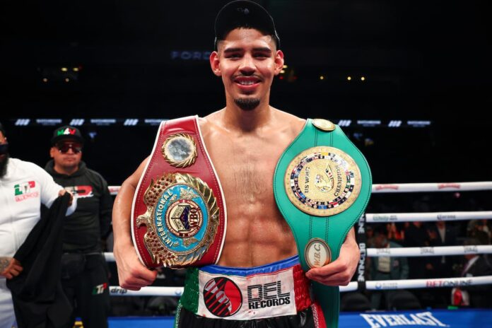 Diego Pacheco posing with his championship belts after a boxing victory