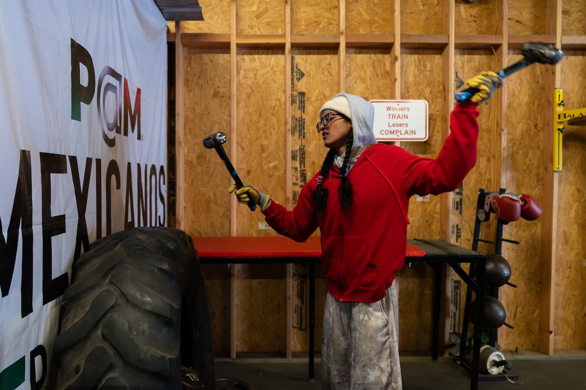 Gabriela Fundora hitting a tire with a hammer during a training workout