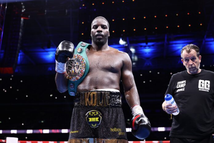 Lawrence Okolie in the boxing ring holding his championship belt after defeating Kevin Lerena