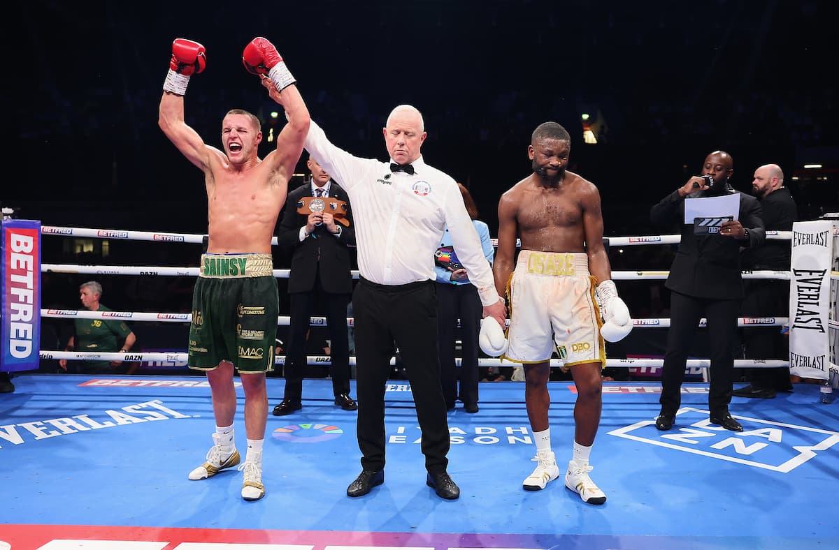 The referee raises Jimmy Sains' hands in victory over Derrick Osaze