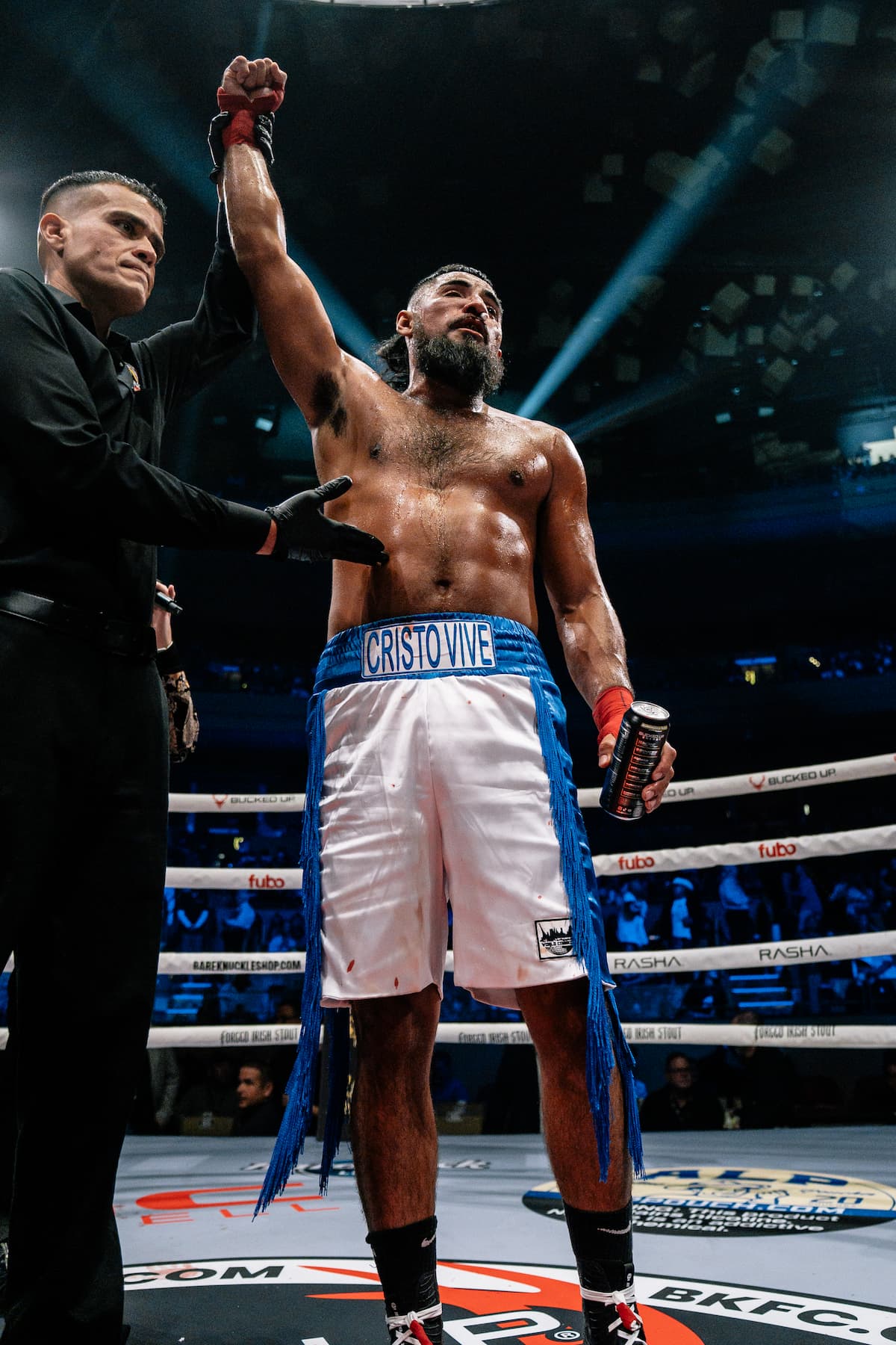 The referee raises Leonel Carrera's hand in victory over Sabah Homasi during their bout