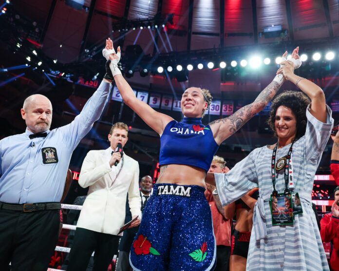 Tammara Thibeault raises her hands in victory after a boxing match