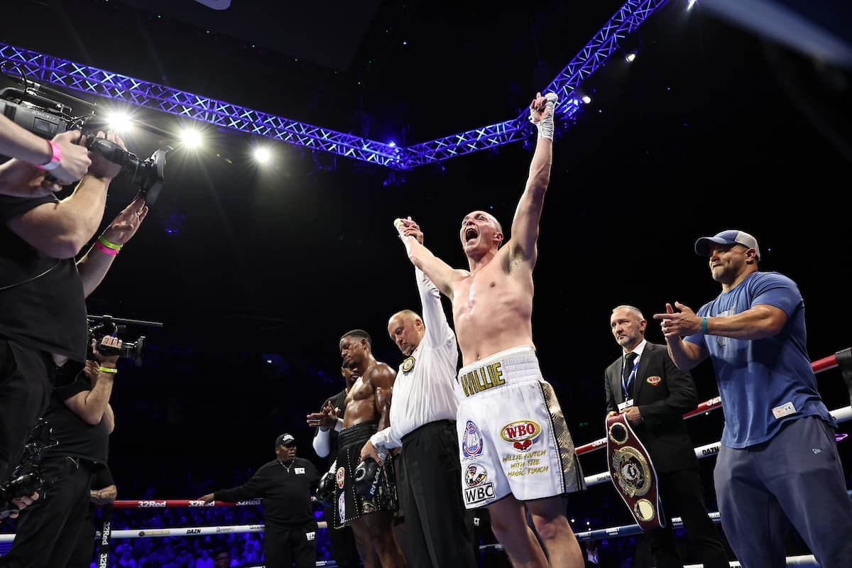 The referee raises Willy Hutchinson's hand in victory after his boxing match against Ezra Taylor