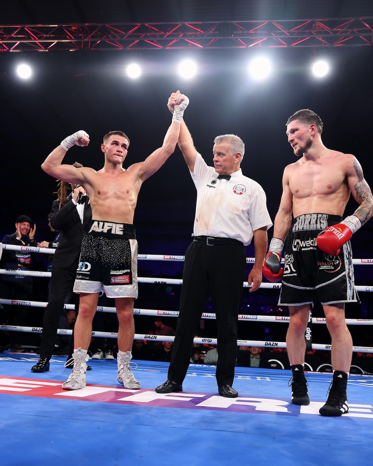 The referee raises Alfie Middlemiss's hand in victory over Lewis Morris during their boxing match