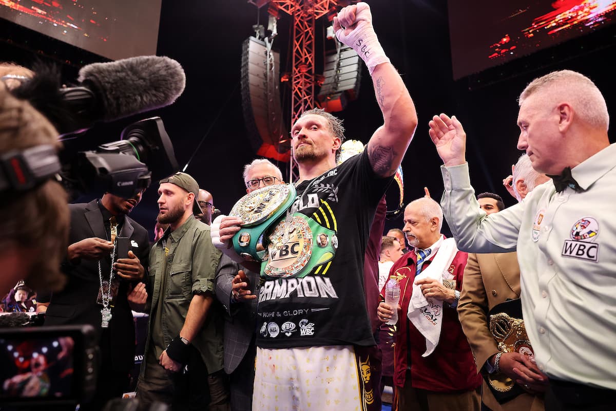 Oleksandr Usyk holding belt and raising hand in victory