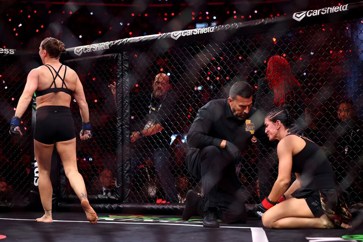 Ronda Rousey walking off as Gina Carano is down on the canvas
