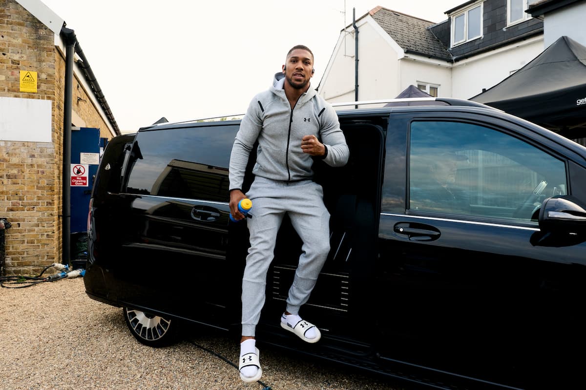 Anthony Joshua poses in front of a minibus after arriving in London