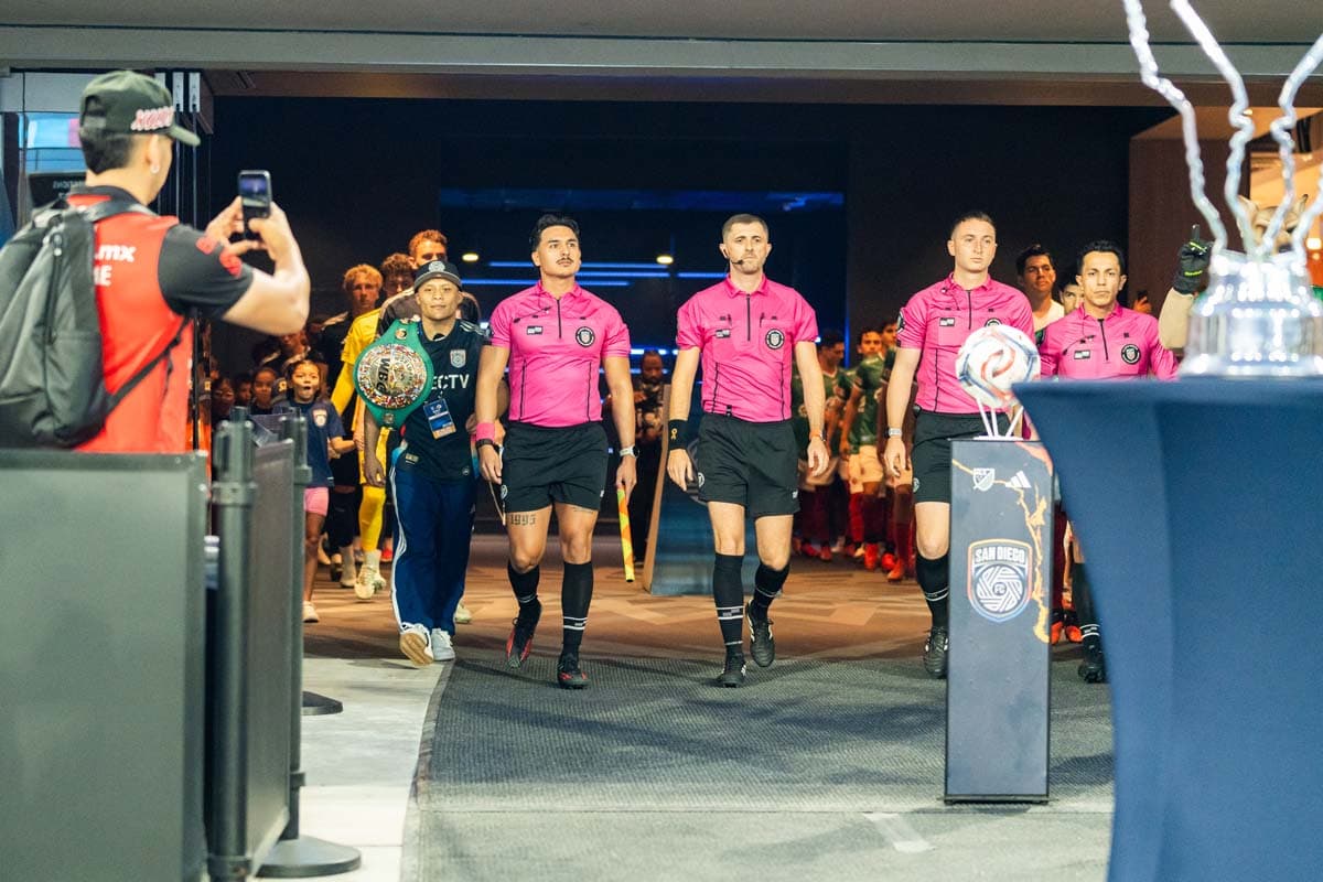 Isaac Cruz walks onto the stadium field with game officials at Snapdragon Stadium
