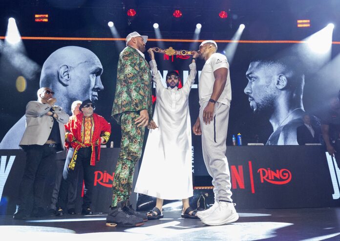 Tyson Fury and Anthony Joshua face off with Turki Alalshikh holding the Battle of Britain championship belt between them