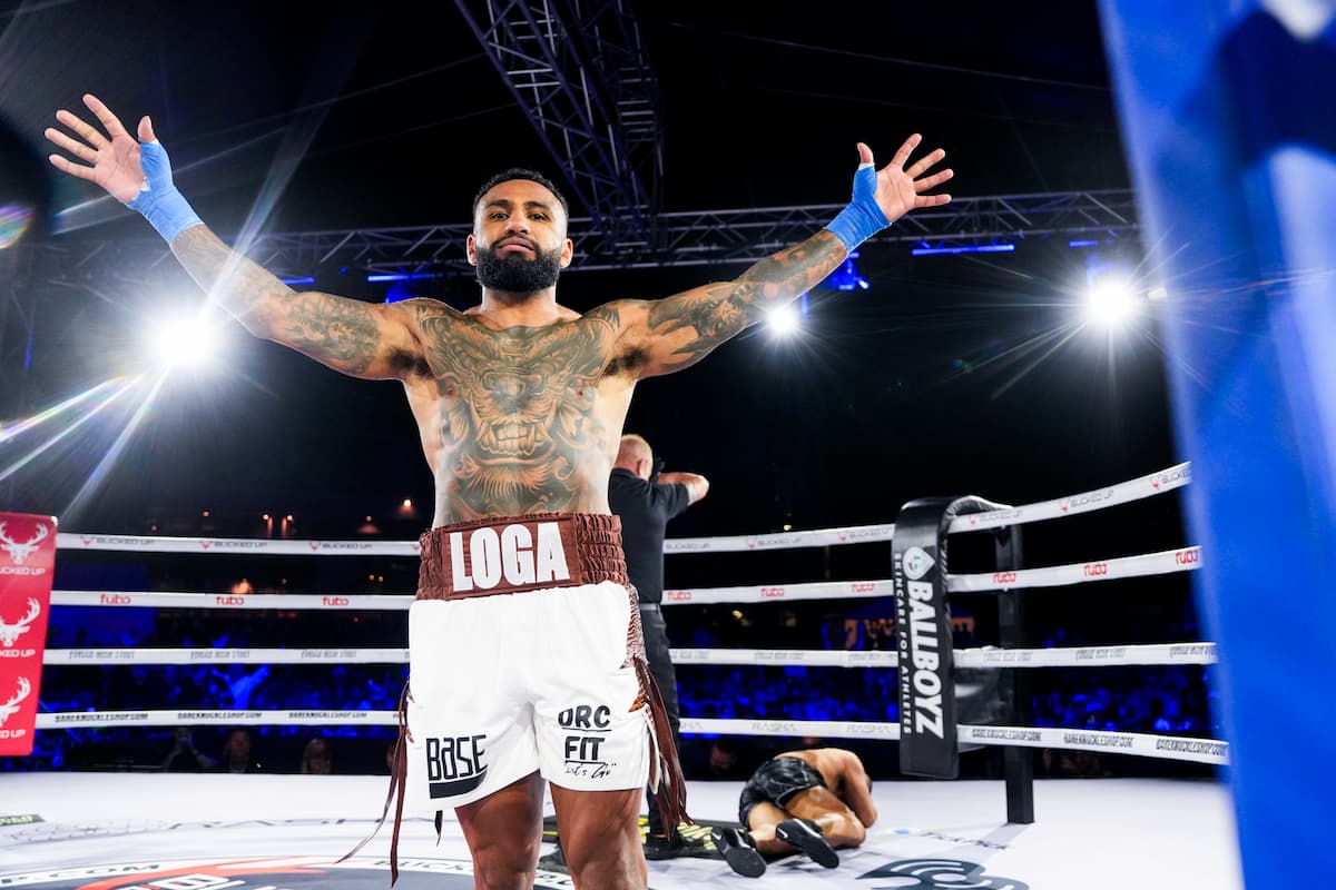 Mario Loga celebrates his victory with his hands raised as Alvin Kanehailua lies on the canvas